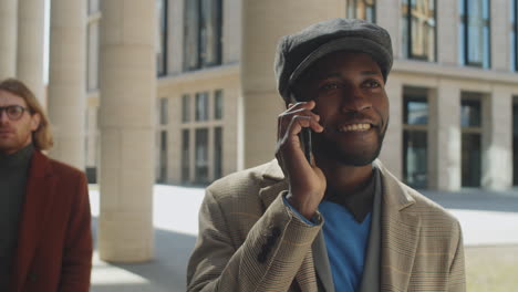 Hombre-De-Negocios-Afroamericano-Caminando-Al-Aire-Libre-Y-Hablando-Por-Teléfono